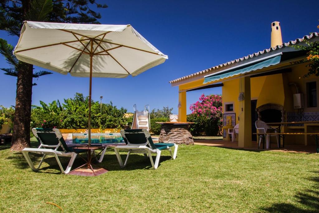 eine Terrasse mit einem Tisch, Stühlen und einem Sonnenschirm in der Unterkunft Quinta Vita - Vila Limao in Almancil