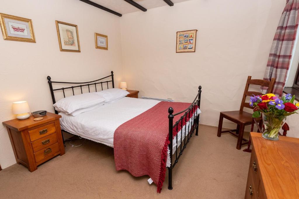 a bedroom with a bed and a table with flowers at Providence Cottage in Woolacombe