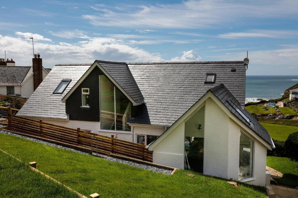 a house with a wooden fence next to the ocean at The White Cottage in Woolacombe