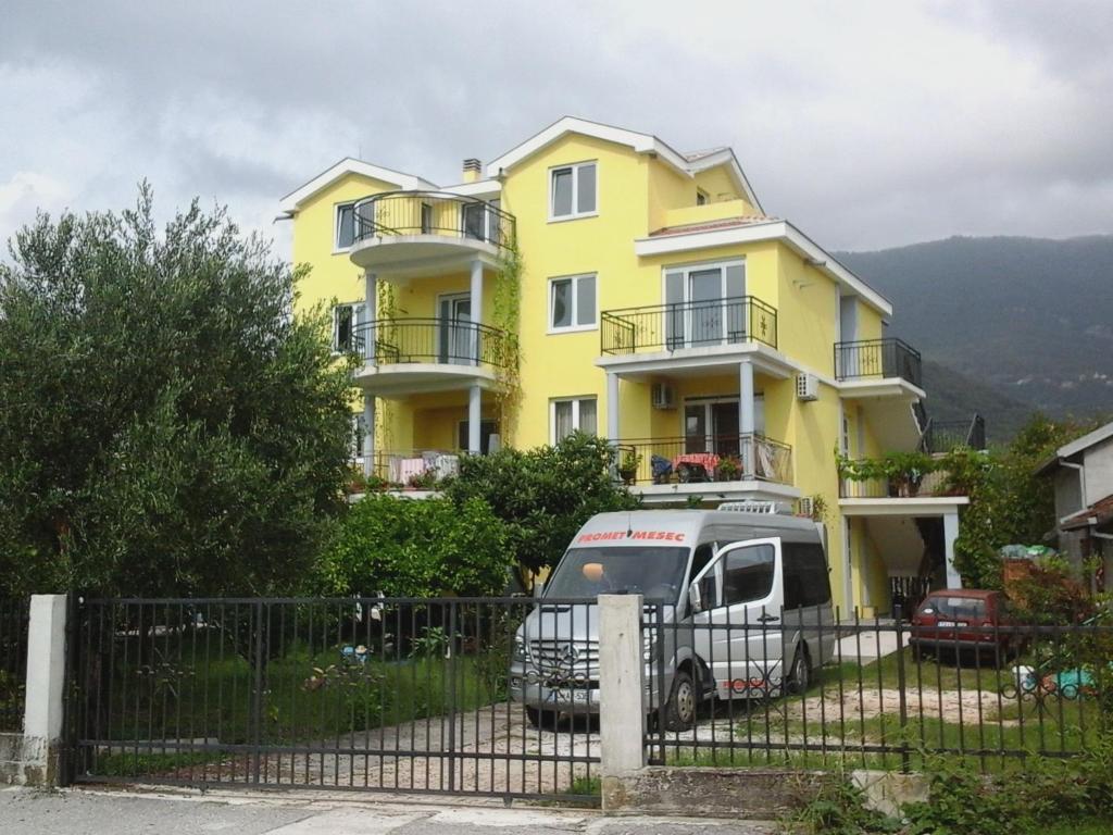 a truck parked in front of a yellow house at Apartments Olga in Tivat