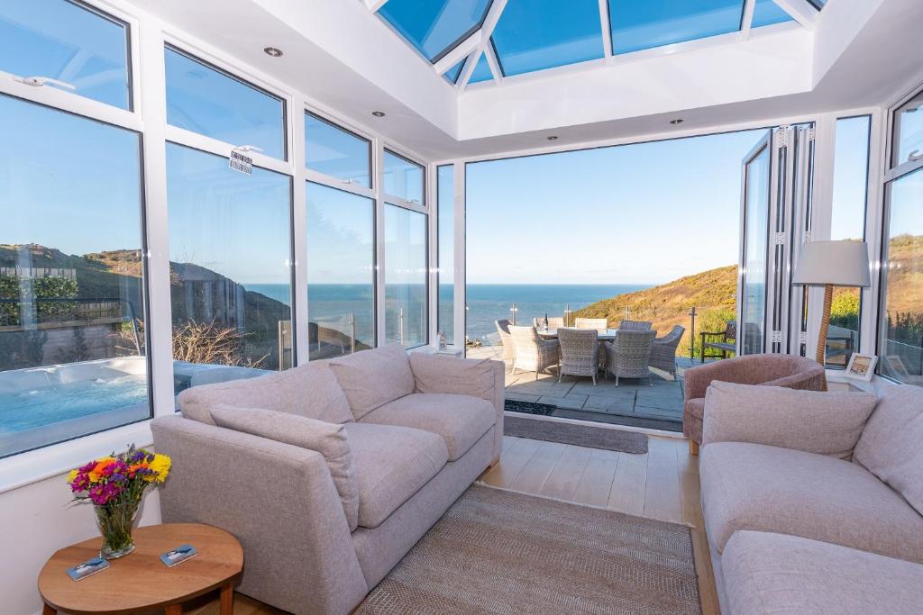 a living room with a couch and chairs and windows at Heatherdale in Mortehoe