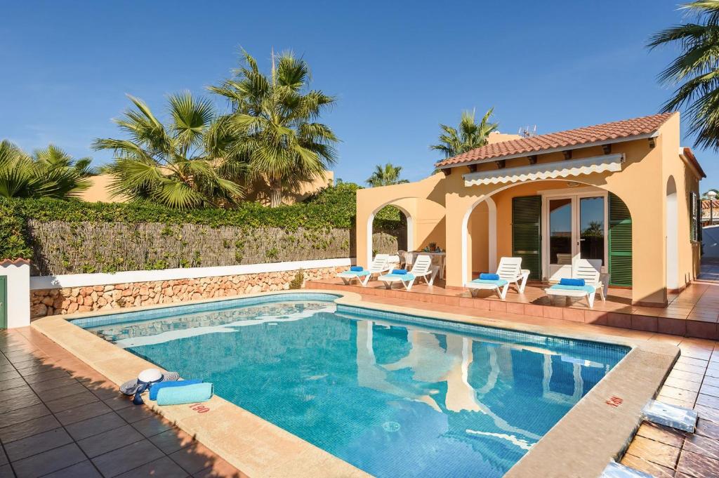 una piscina con sillas y una casa en Villa Mango by Villa Plus, en Cala'n Bosch