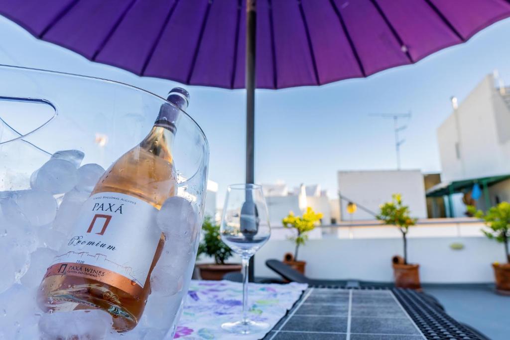 een fles wijn op een tafel met een paraplu bij Casa Terraço in Fuzeta