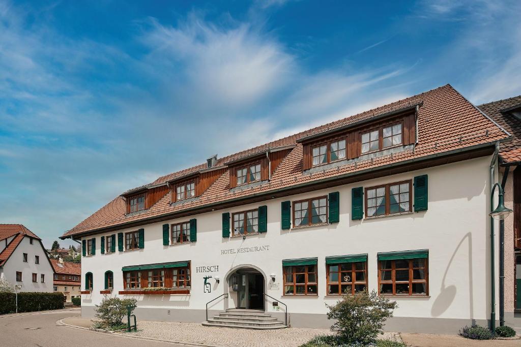 ein großes weißes Gebäude mit braunem Dach in der Unterkunft Romantik Hotel & Restaurant Hirsch in Sonnenbühl