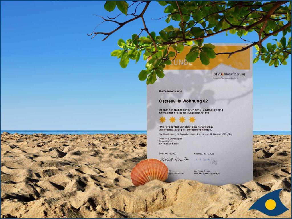 un cartel en la playa con una cáscara en la arena en Ostseevilla Whg 02 en Bansin