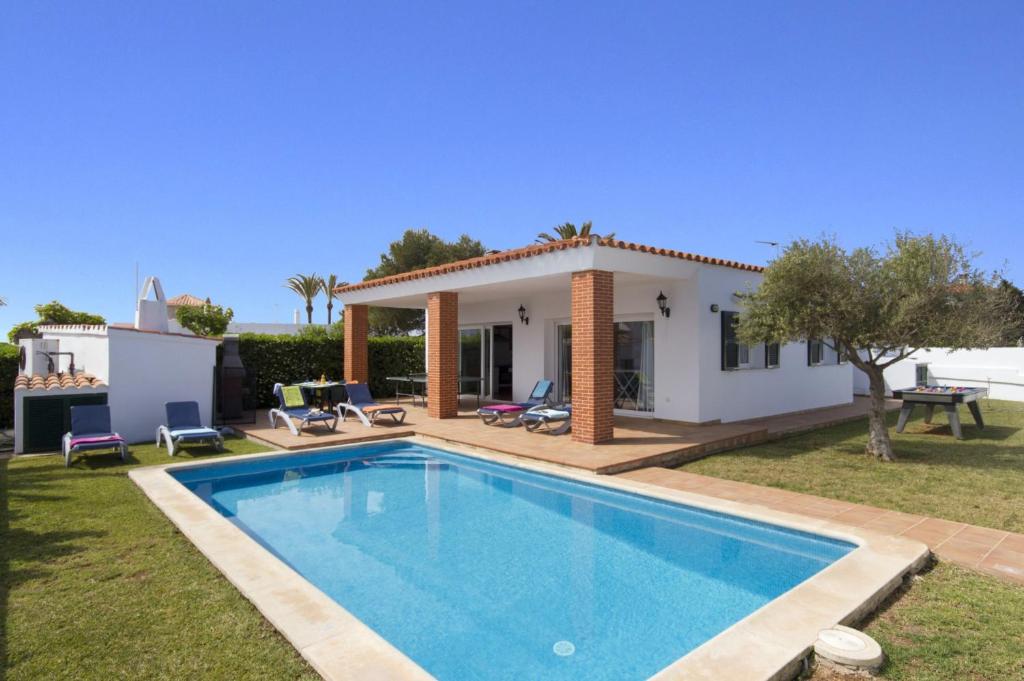 a villa with a swimming pool in front of a house at Villa Ondinas by Villa Plus in Cala en Forcat