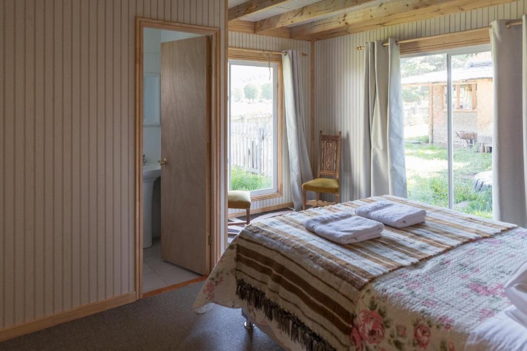 ein Schlafzimmer mit einem Bett und einem großen Fenster in der Unterkunft La Casona, Baño Privado in Villa Cerro Castillo