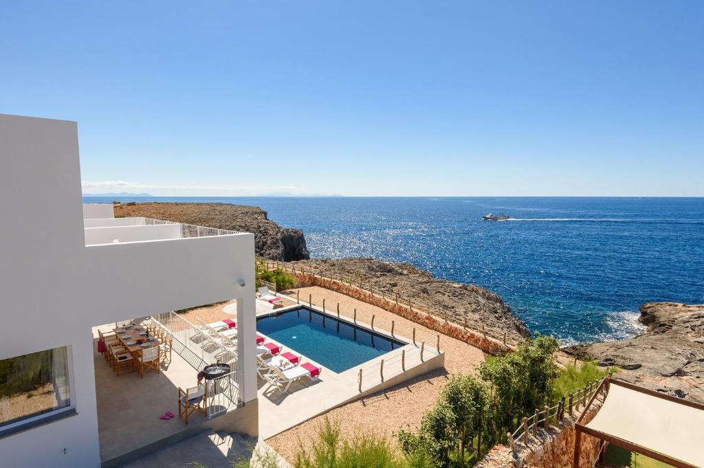 une maison avec une piscine à côté de l'océan dans l'établissement Villa Aguamarina by Villa Plus, à Cala en Forcat