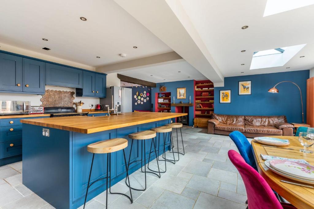 a kitchen with blue cabinets and a bar with stools at Church Lane Cottage - Norfolk Holiday Properties in Filby