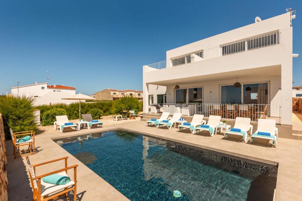 eine Villa mit einem Pool und Liegestühlen in der Unterkunft Villa Amatista by Villa Plus in Cala en Forcat