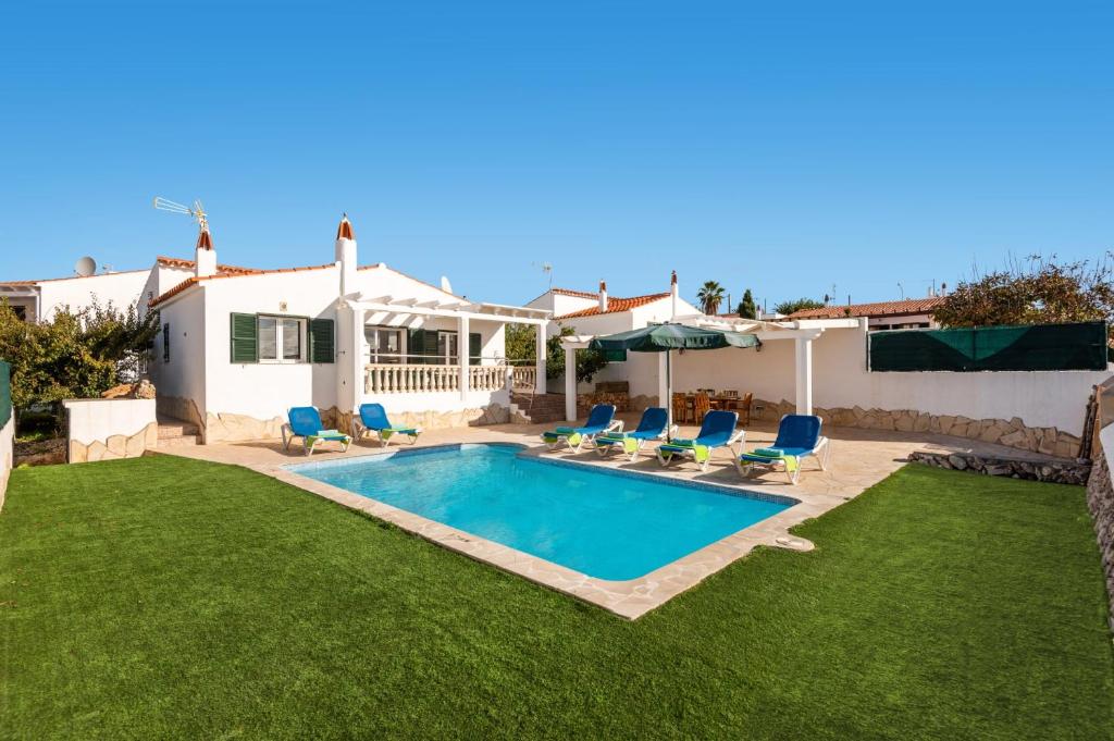a swimming pool in a yard with chairs and a house at Villa Santi III by Villa Plus in Cala'n Porter