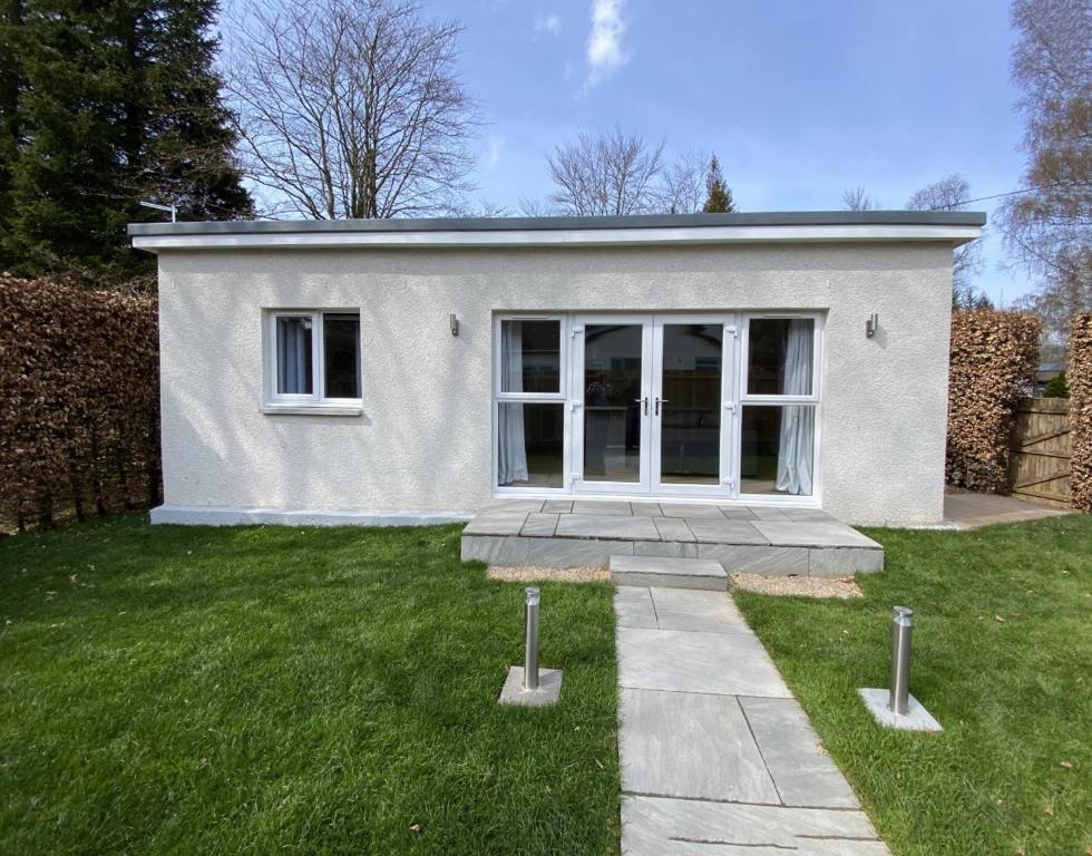 a small white house with a grass yard at White Cottage - Cosy Holiday Cottage in Drymen, Loch Lomond & Trossachs in Drymen
