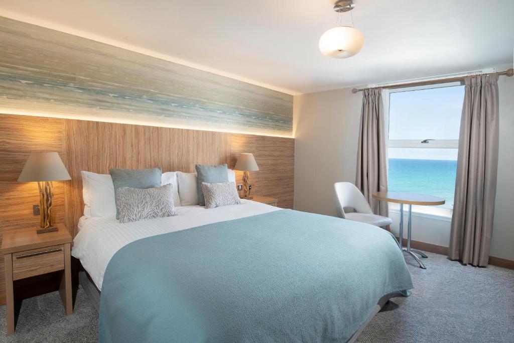 a bedroom with a large bed with a view of the ocean at Fistral Beach Hotel and Spa - Adults Only in Newquay