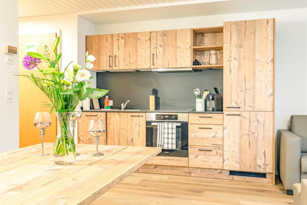 una cucina con armadi in legno e un tavolo con un vaso di fiori di Kehr Apartment - Aare Jungfrau AG a Grindelwald