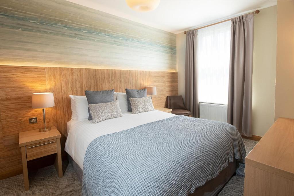 a bedroom with a large bed and a window at Fistral Beach Hotel and Spa - Adults Only in Newquay
