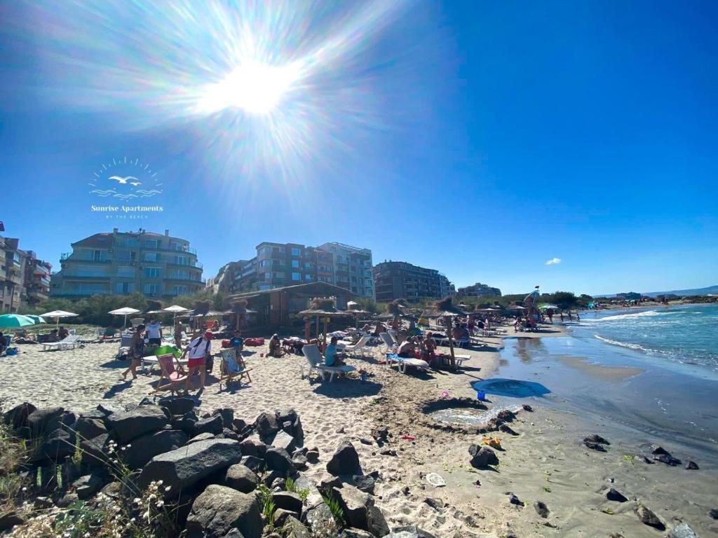 un grupo de personas en una playa con el sol en Sunrise Apartments, Pomorie en Pomorie