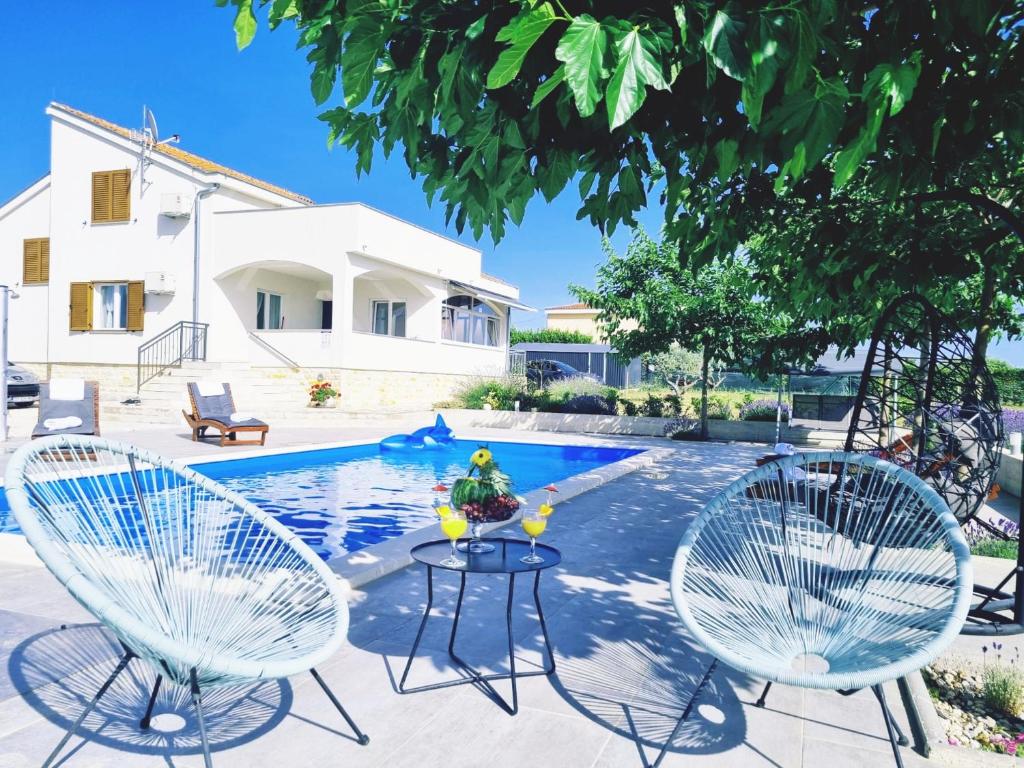 duas cadeiras e uma mesa em frente a uma piscina em Villa Jelena em Zadar