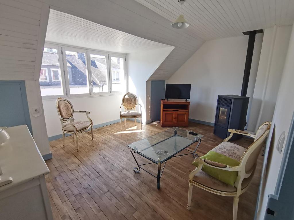 a living room with chairs and a table and a tv at Mignon appartement sous les toits in Guéméné-sur-Scorff
