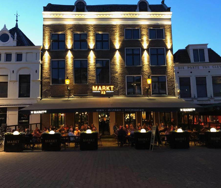 a large building with people sitting at tables in front of it at Hotel Markt23 in Sneek