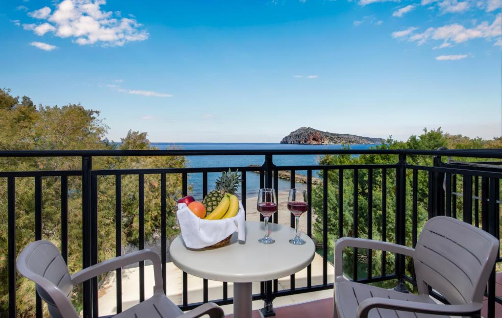 Margarita Beach Hotel في أييا مارينا نيا كيذونياس: طاولة مع سلة من الفواكه وكؤوس النبيذ على شرفة