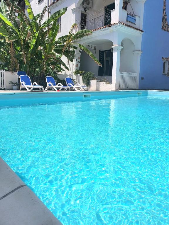 a swimming pool with chairs and a house at Cedro - Appartamento in residence con piscina condivisa in Orosei