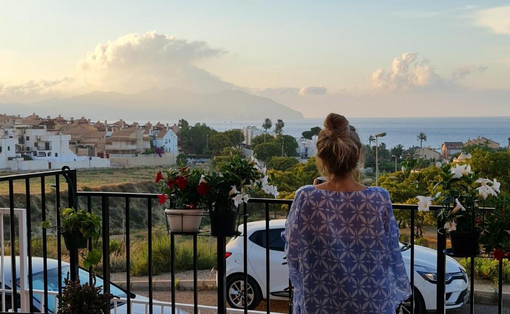 kobieta stojąca na balkonie z widokiem na ocean w obiekcie SunRise Den, a pie de playa, vista al mar y piscina w mieście Puerto de Mazarrón
