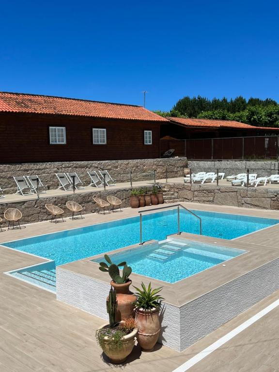 a swimming pool with chairs and a building at Camping Preguntoiro in Sanxenxo