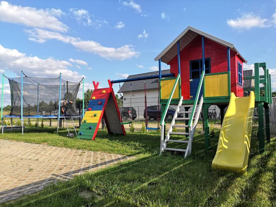 ein Spielplatz mit bunten Spielgeräten im Gras in der Unterkunft Słoneczny Raj Apartamenty Domki apartamentowe in Sarbinowo