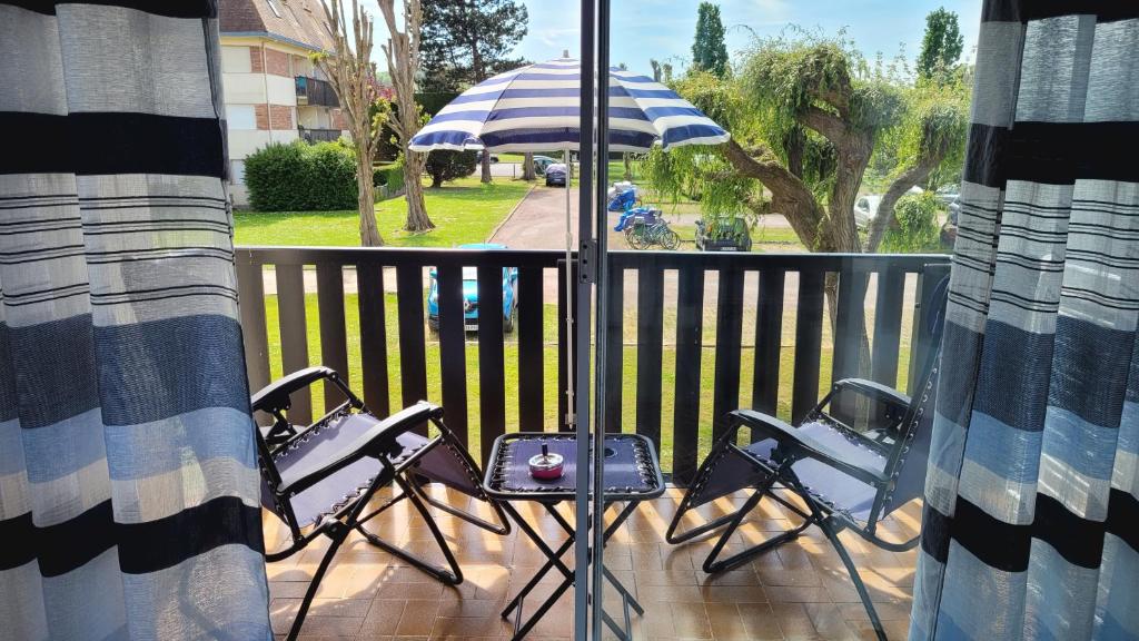 - un balcon avec 3 chaises et un parasol dans l'établissement Les Portes de la Mer, à Villers-sur-Mer