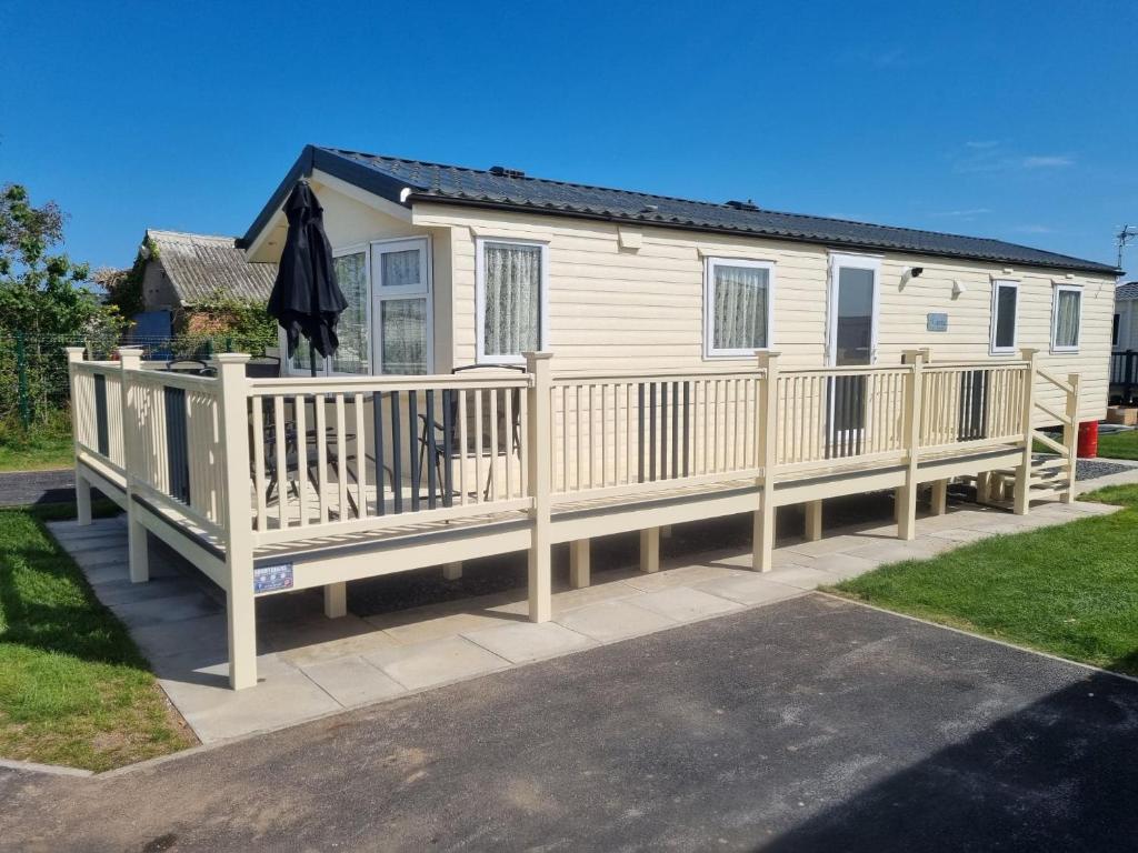 a mobile home with a deck and a house at 8 BERTH DELUXE PG153 GOLDEN PALM CHAPEL ST LEONARDS in Chapel Saint Leonards