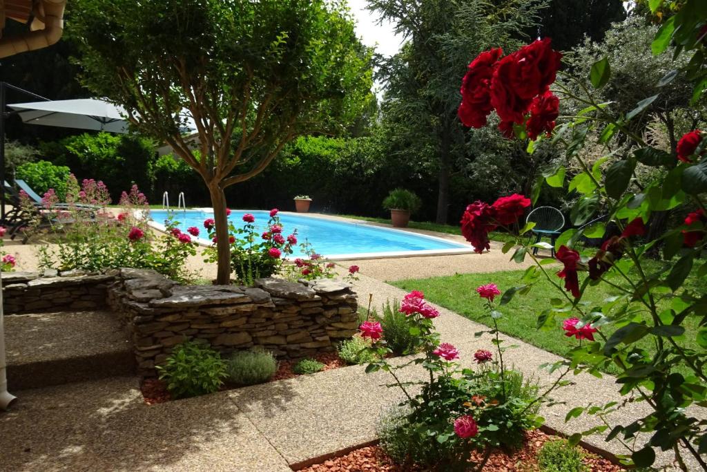 un jardin avec une piscine et des fleurs dans l'établissement La Mésange Bleue - piscine privée, à LʼIsle-sur-la-Sorgue
