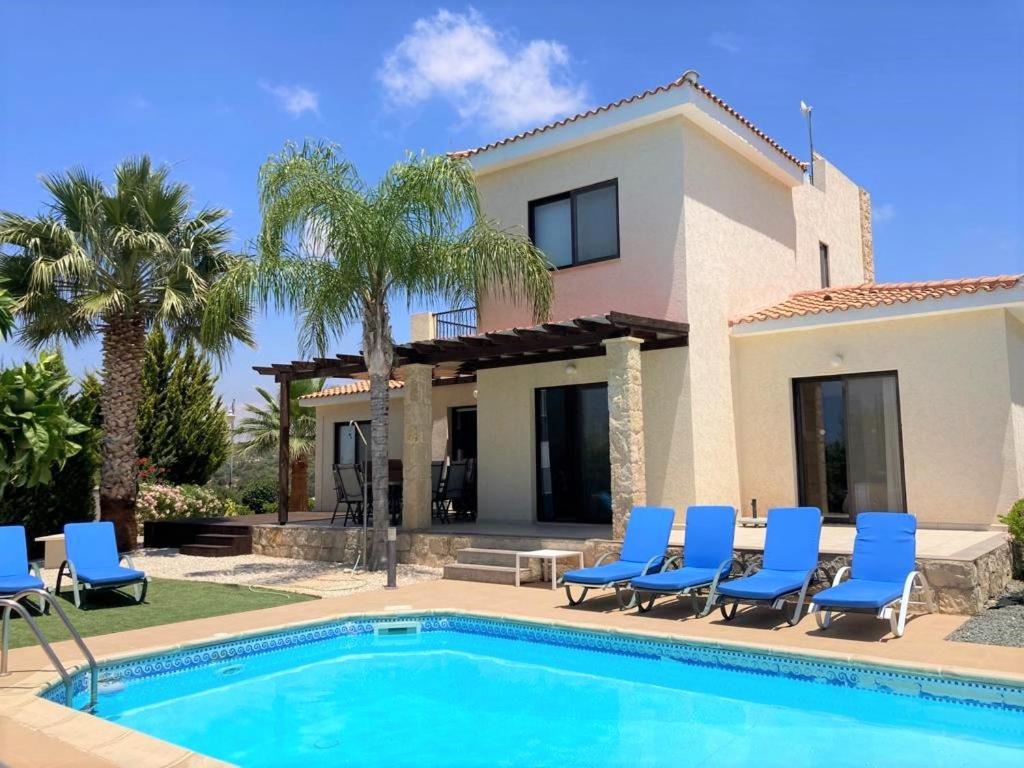 a villa with a swimming pool and blue chairs at Hill View Villa 5 in Kouklia