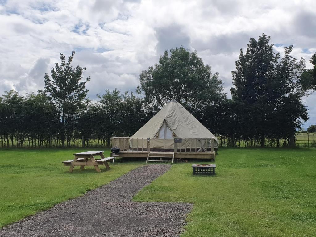 a tent and a picnic table in a field at Swanns Bridge Glamping in Limavady