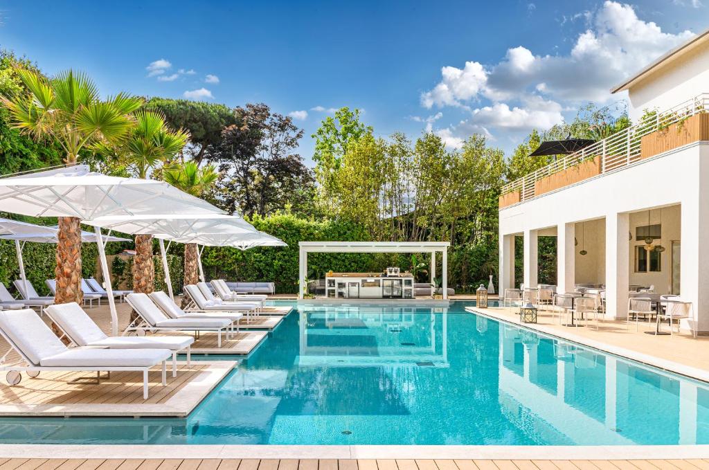 einen Pool mit Stühlen und Sonnenschirmen neben einem Haus in der Unterkunft Resort Miramonti in Forte dei Marmi