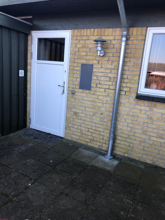 a white door on the side of a brick building at Langø, ferielejlighed in Nakskov