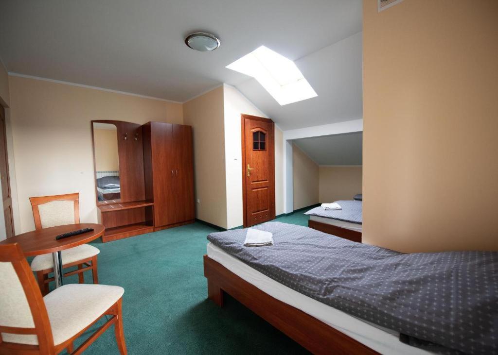 um quarto de hotel com uma cama e uma mesa e cadeira em Pokoje Horyzont em Jarosław