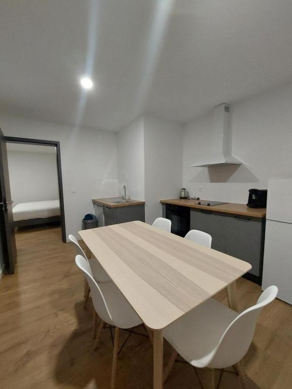 kuchnia z drewnianym stołem i białymi krzesłami w obiekcie Les Lodges du Revermont w mieście Passenans