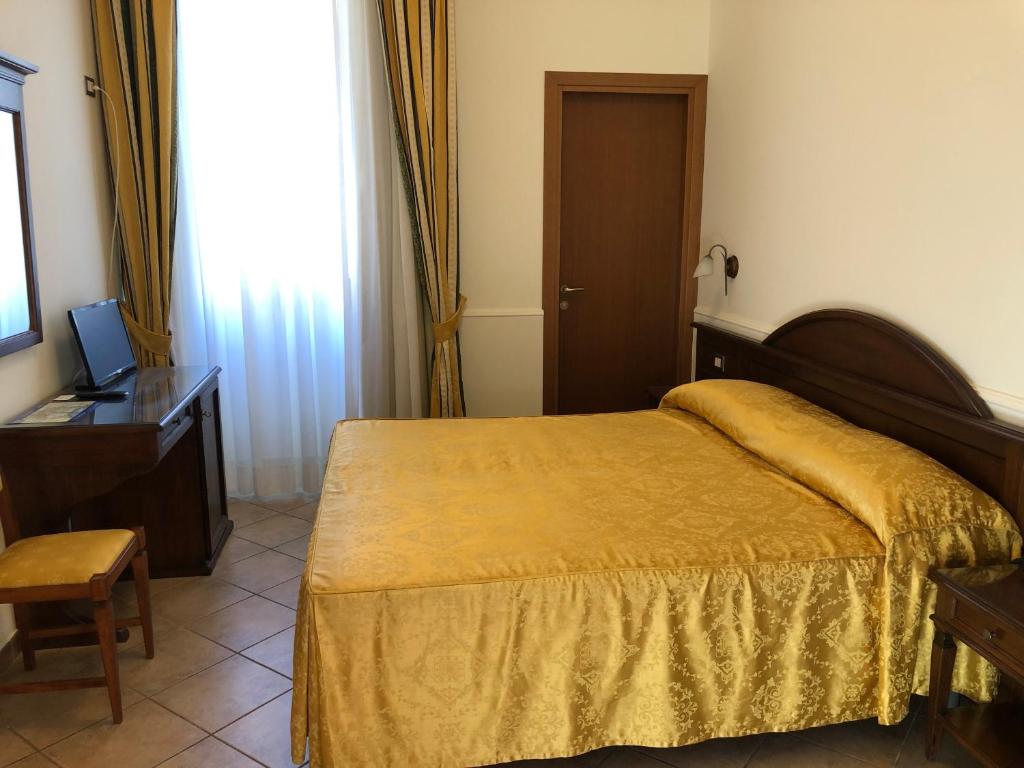 - une chambre avec un lit, un bureau et une télévision dans l'établissement Hotel Zodiaco, à Bolsena