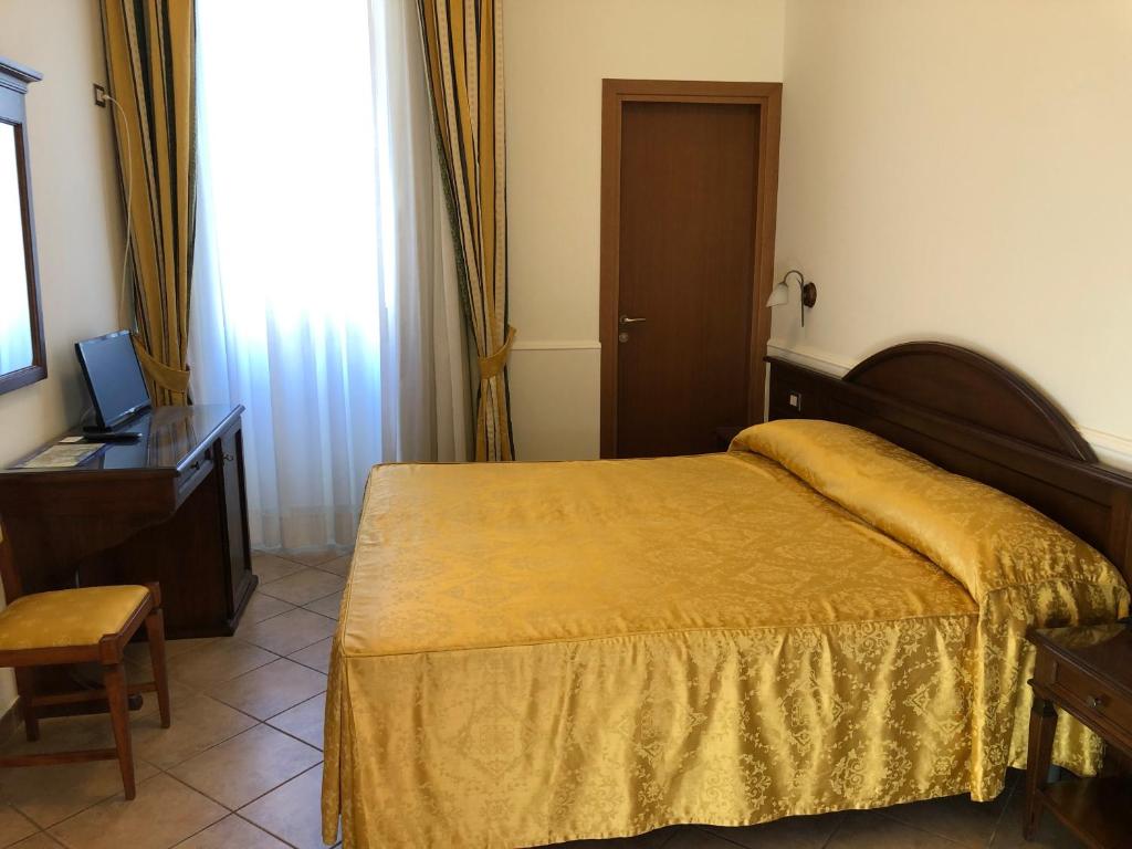 a bedroom with a bed and a desk and a television at Hotel Zodiaco in Bolsena