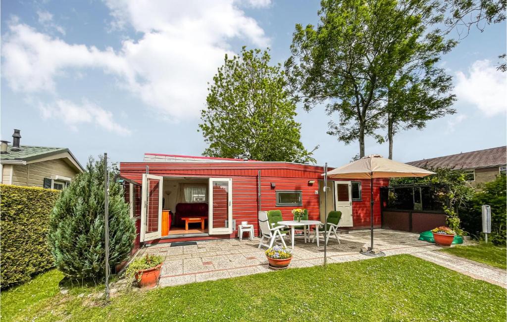 een rood tiny house in een tuin met een patio bij Beautiful Home In Tzummarum With 2 Bedrooms, Outdoor Swimming Pool And Wifi in Tzummarum