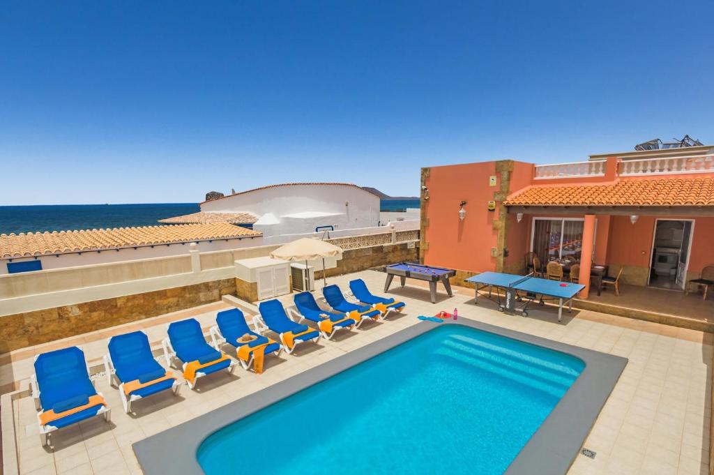 piscina con sedie a sdraio e oceano di Villa Tamarindos by Villa Plus a La Oliva