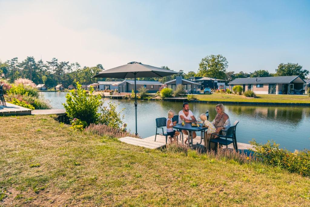 a group of people sitting at a table by a lake at EuroParcs Zilverstrand in Mol