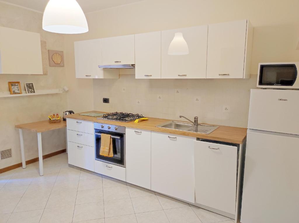 een keuken met witte kasten, een wastafel en een koelkast bij 6 a casa in Milaan
