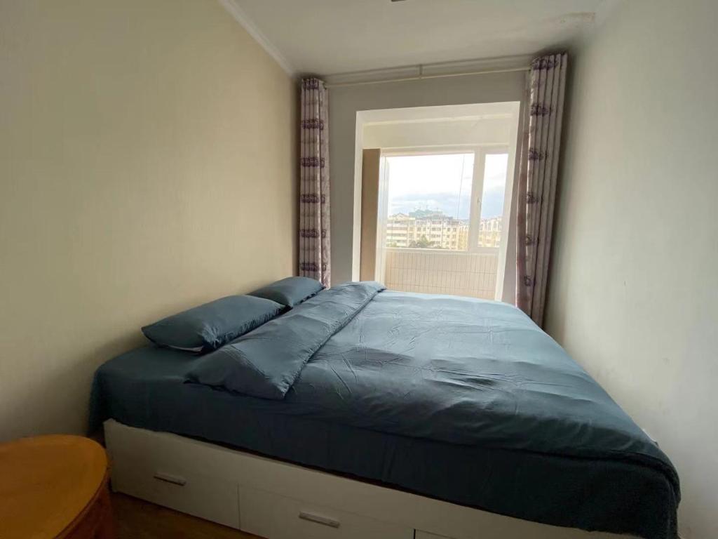 a bedroom with a blue bed with a window at 七零四 in Kunming