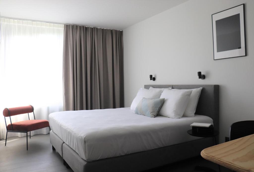 ein Hotelzimmer mit einem Bett und einem Stuhl in der Unterkunft Hotel National Antwerp in Antwerpen