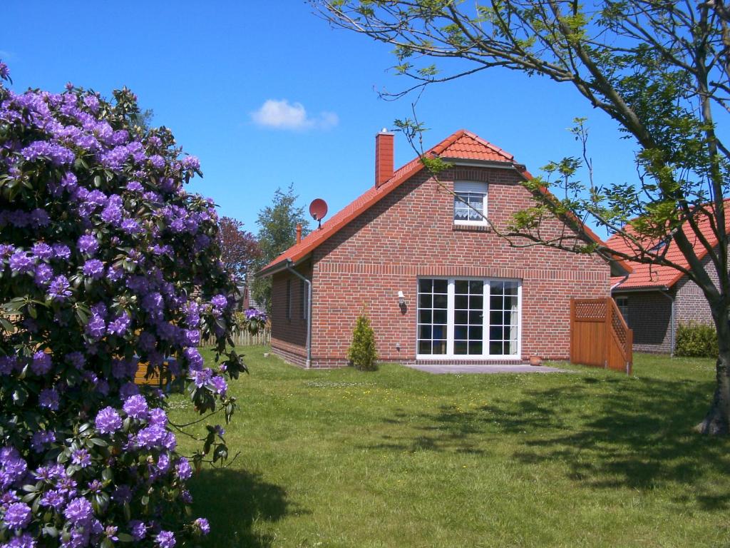 una casa de ladrillo rojo con ventana y flores púrpuras en Eschenhaus, en Norden