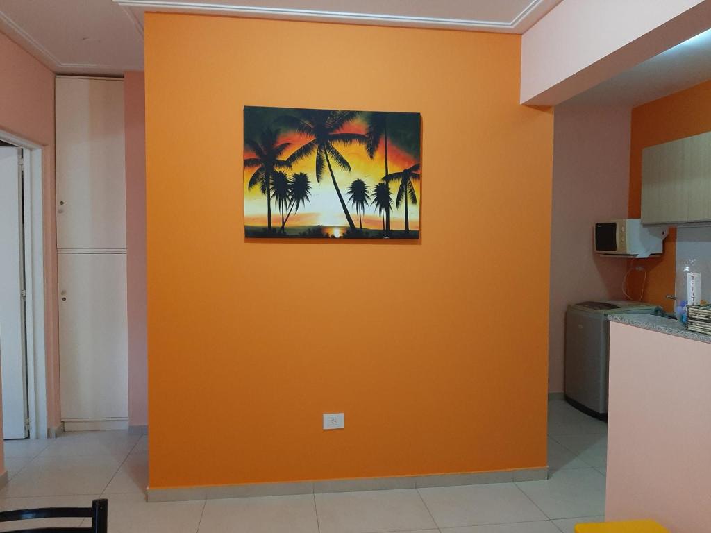 an orange wall in a kitchen with a picture of palm trees at Departamento de la Bahia in Bahía Blanca