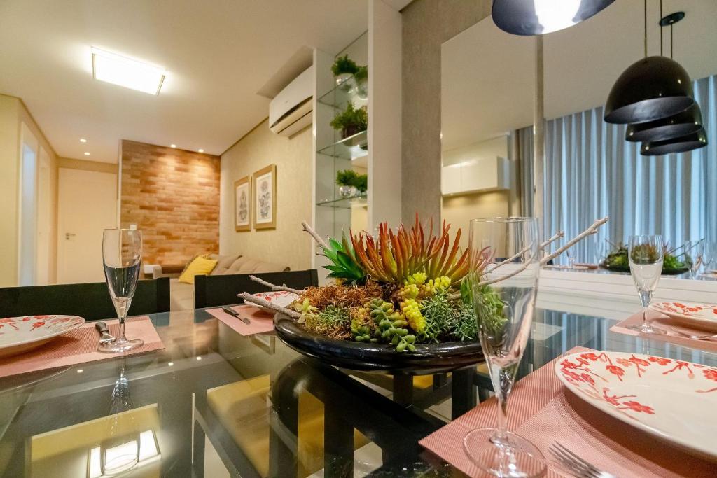 a dining room with a table with a bowl of flowers at Varandas do Atlântico, Condo Frente Mar com Piscina Climatizada - 3 quartos 6 pessoas in Bombinhas