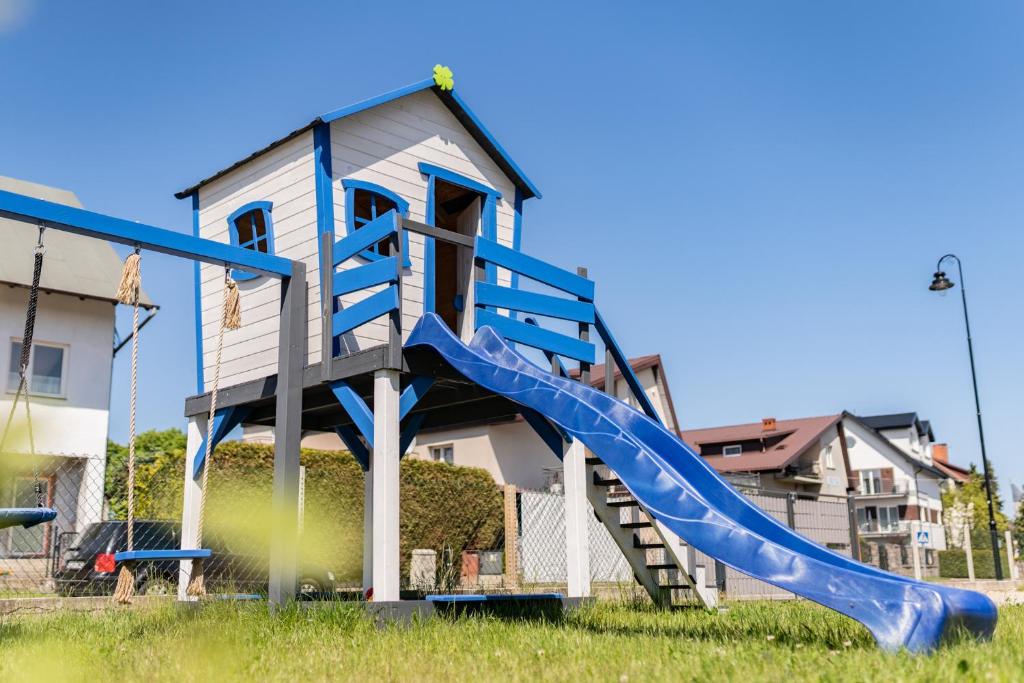 a playground with a blue slide in front of a house at Domki U Rybaka in Łeba