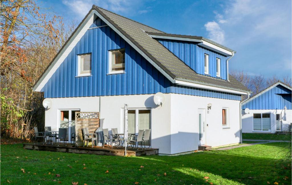 ein blau-weißes Haus mit Stühlen auf einem Rasen in der Unterkunft Ferienhaus 30 Altefhr in Altefähr